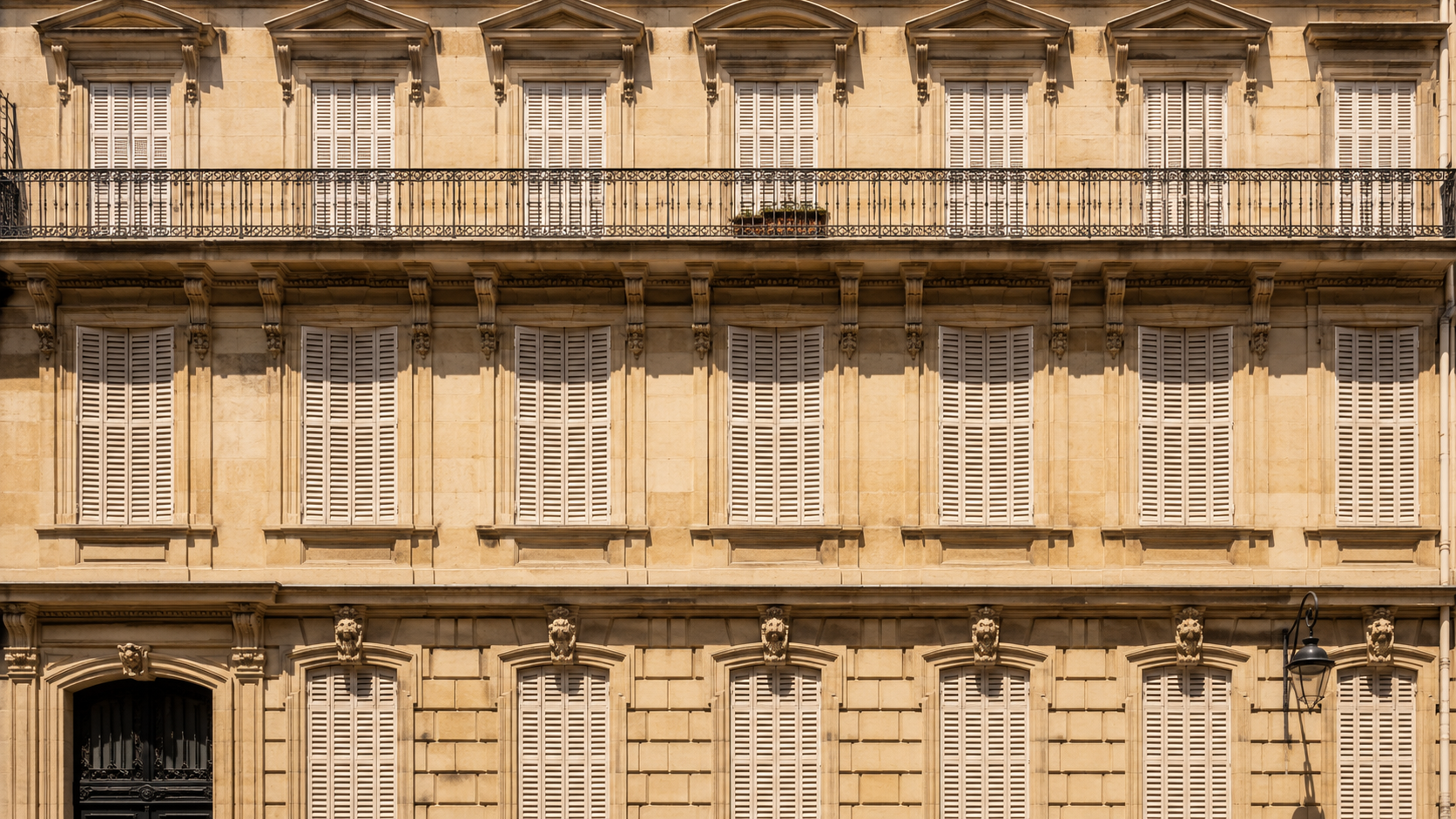 Facade d'immeuble haussmannien aux volets en bois fermes contre le soleil de midi