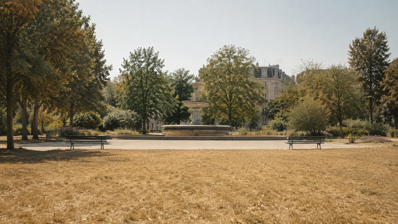 Parc urbain a la pelouse jaunie et fontaine a l'arret pendant la canicule, bancs vides