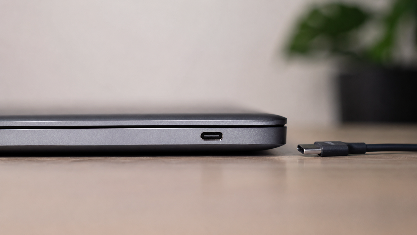 Le port USB-C sur la tranche d'un ordinateur portable fermé, un câble posé à côté