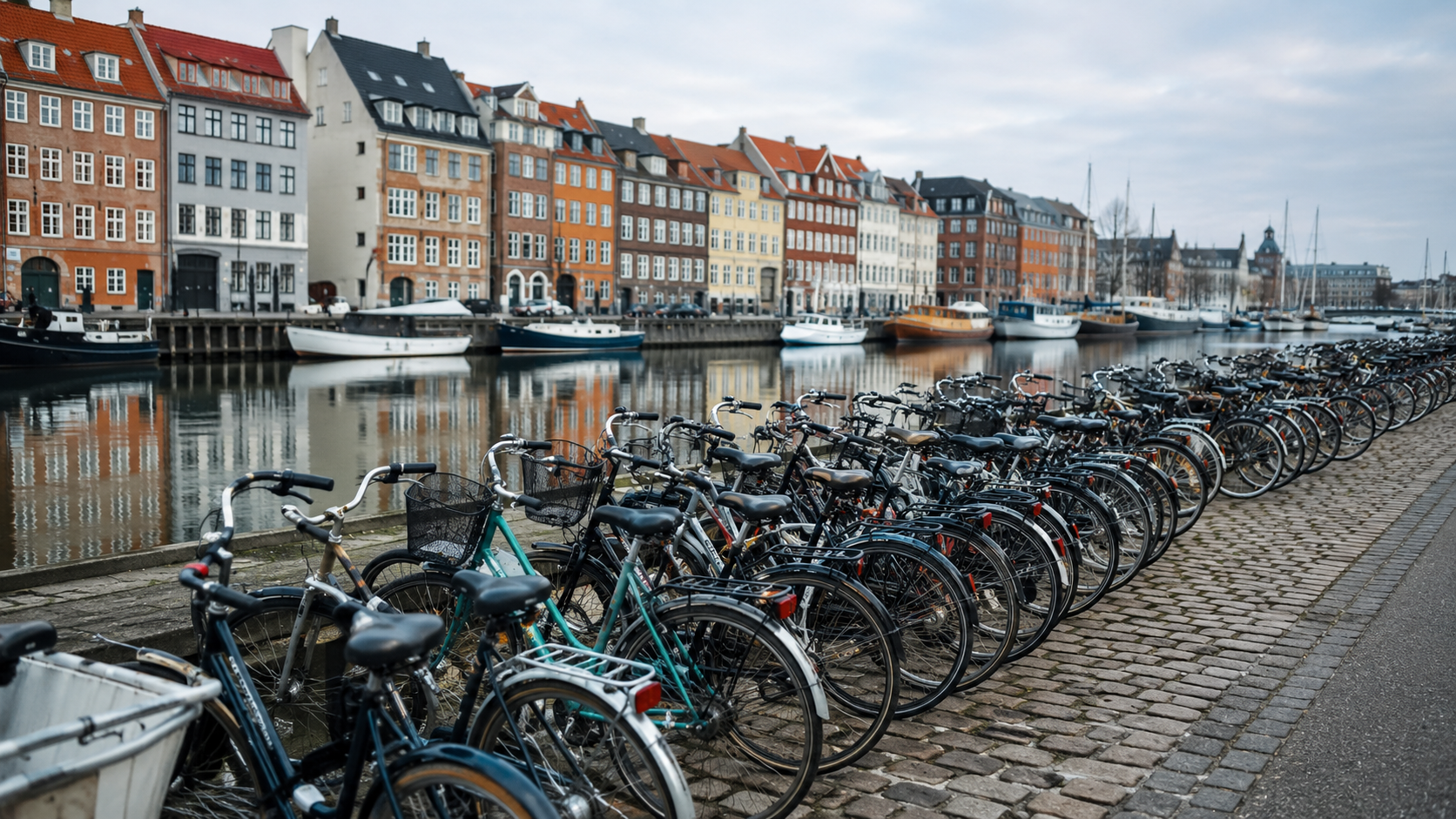 Des dizaines de vélos garés en rangées le long d'un quai de Copenhague, bâtiments portuaires derrière