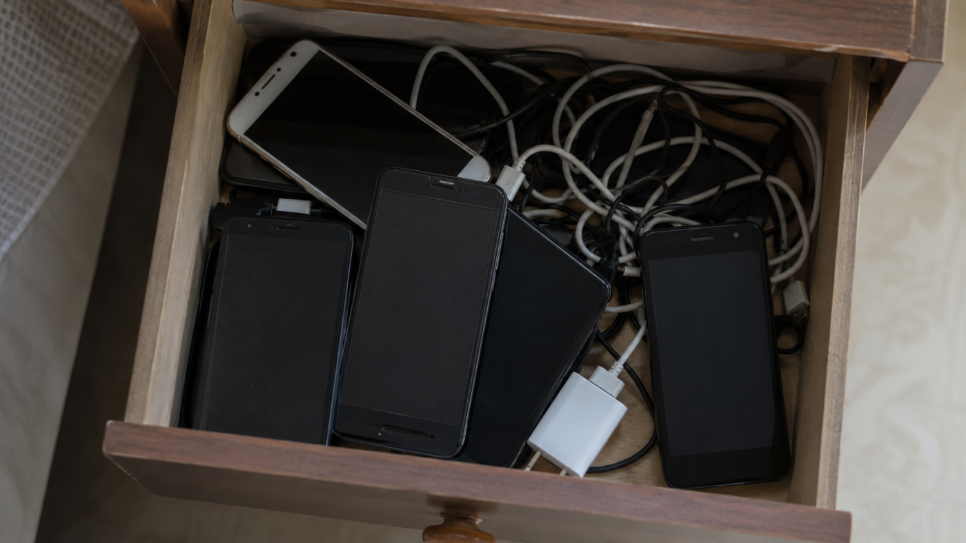 Tiroir ouvert rempli de vieux smartphones et de câbles