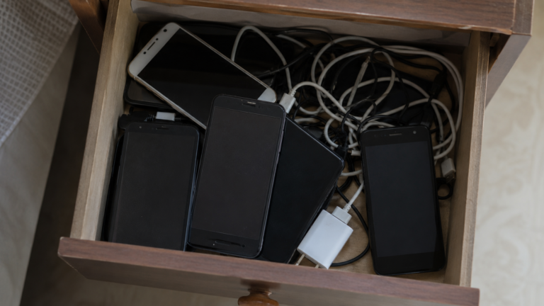 Tiroir ouvert rempli de vieux smartphones et de câbles