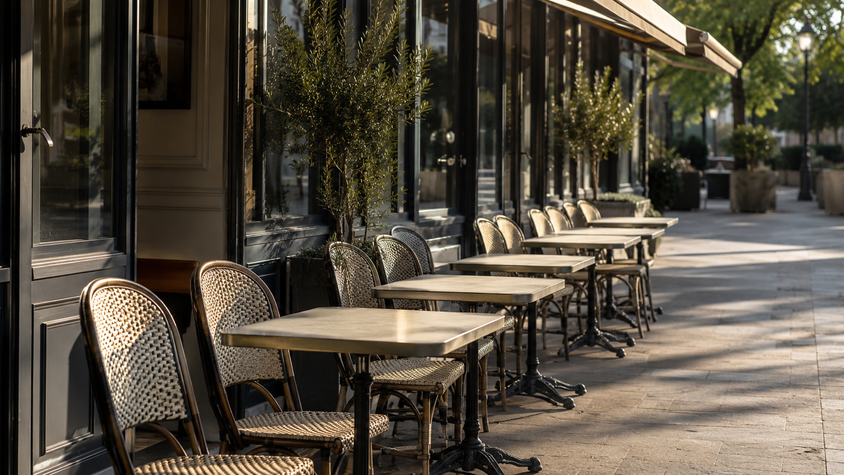 Une terrasse de café vide aux chaises alignées, dans une lumière calme du matin