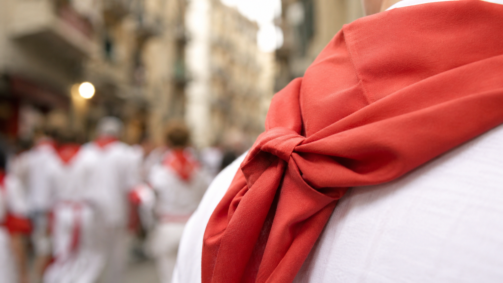 Détail d'un foulard rouge posé sur une manche de chemise blanche