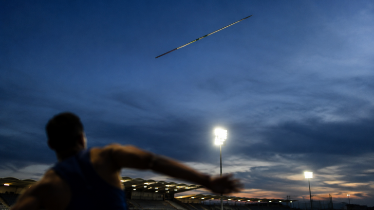 Javelot fige en plein vol dans un ciel bleu du soir au-dessus d'un stade eclaire