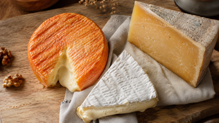 Planche en bois avec une selection de fromages francais, brie fondant, fromage a croute lavee et pate dure affinee