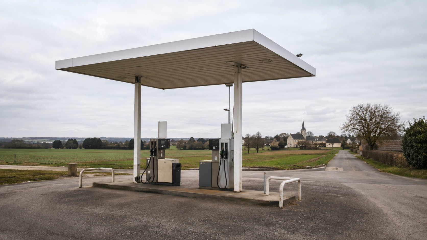 Une petite station-service à deux pompes au bord d'une route de campagne, à l'entrée d'un village