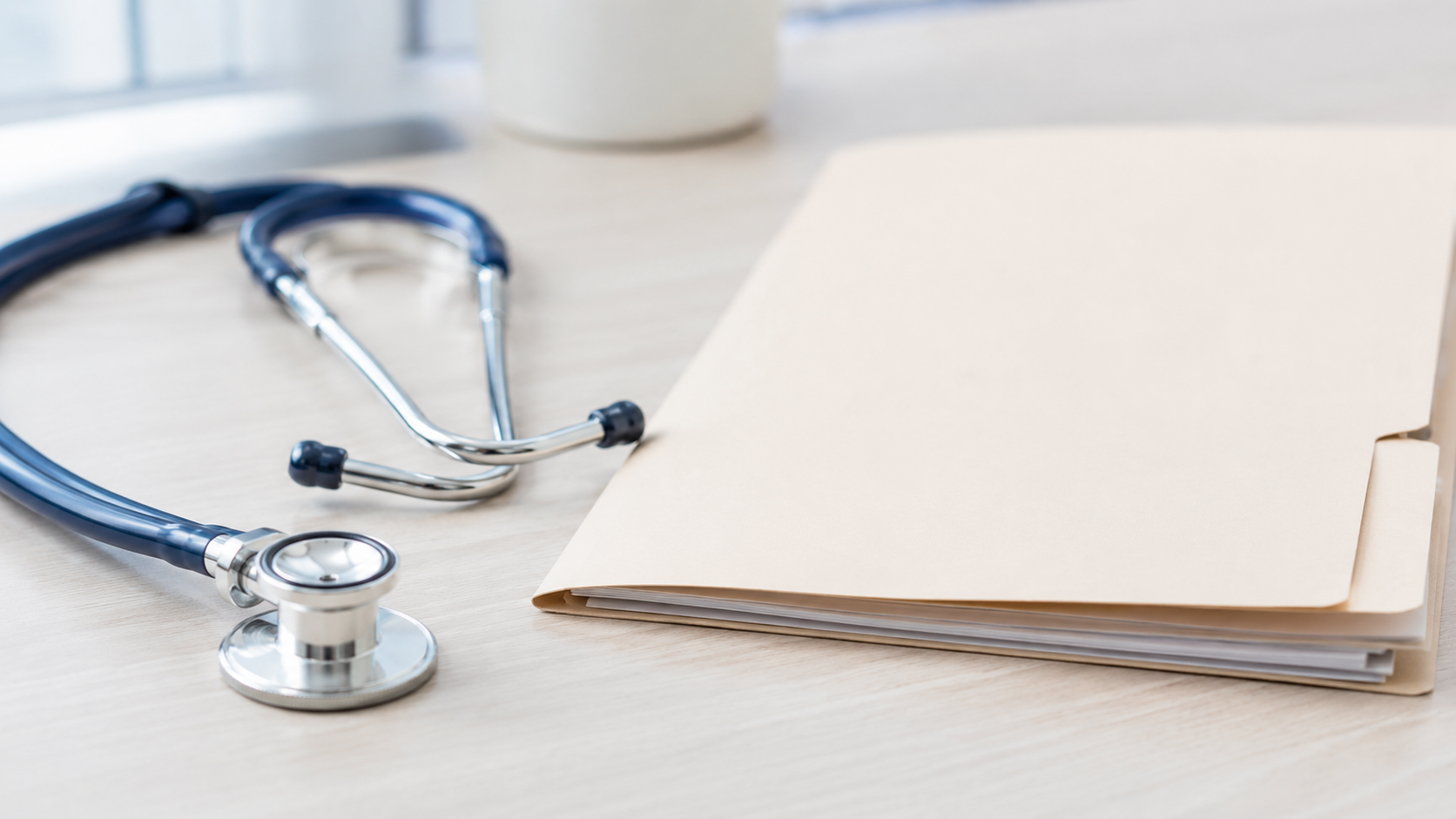Un stéthoscope posé sur un bureau médical clair à côté d'un dossier fermé