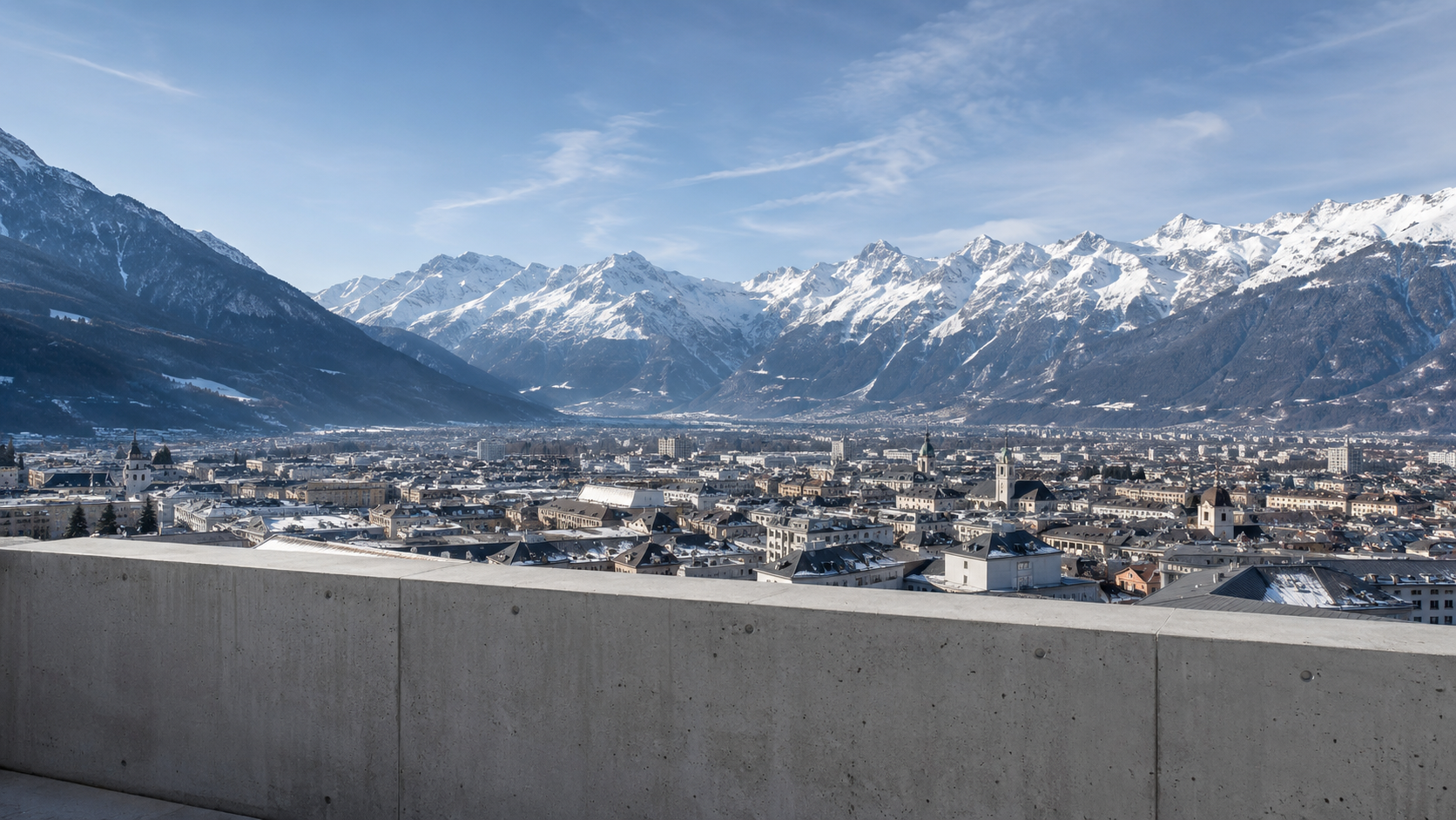 Panorama depuis une rambarde d'observation en béton sur les toits d'une ville alpine cernée de montagnes enneigées