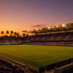 Stade de football americain moderne et vide au crepuscule, projecteurs allumes, palmiers en silhouette et ciel violet