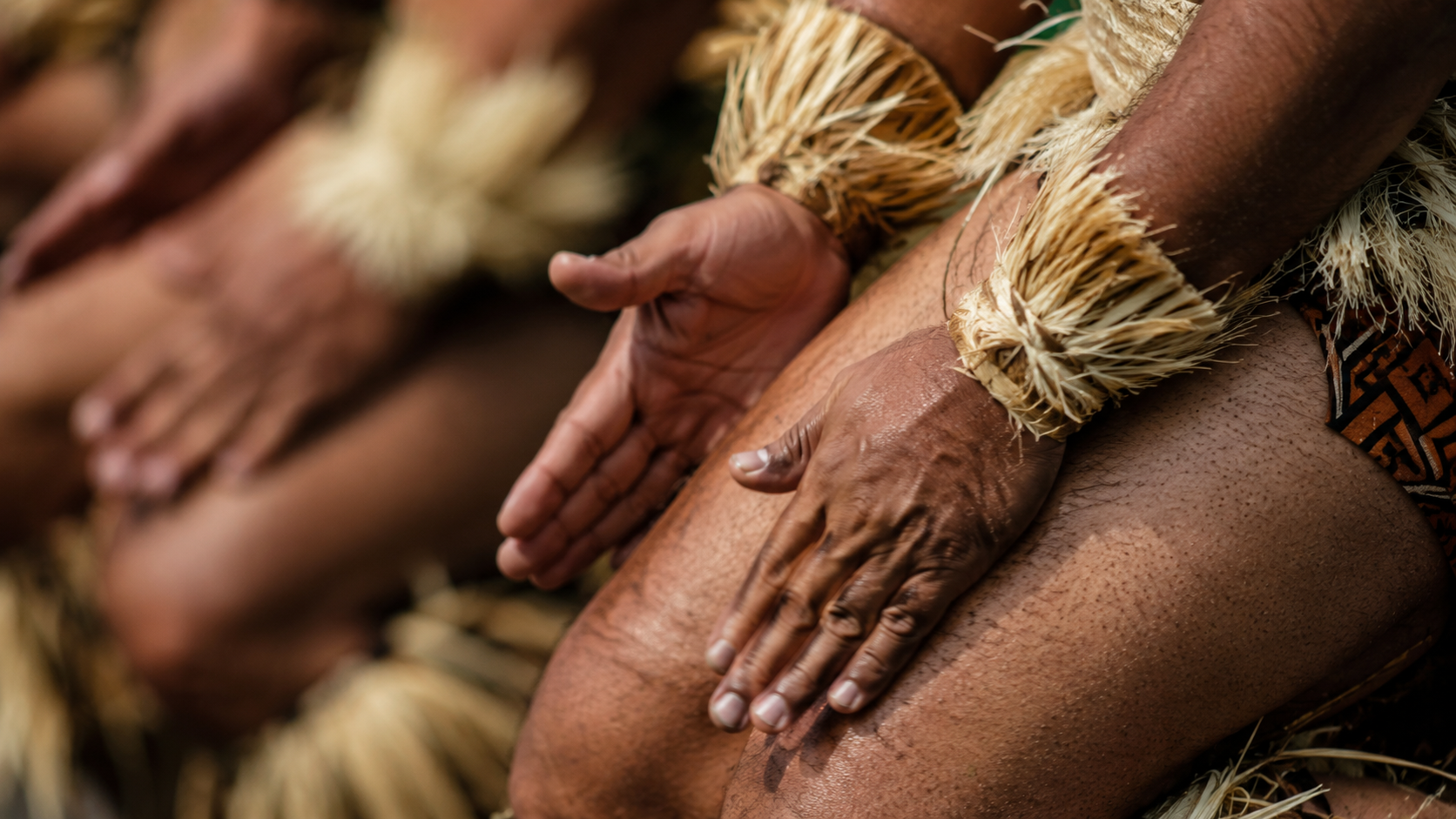 Gros plan de mains frappant les cuisses pendant une danse cérémonielle du Pacifique