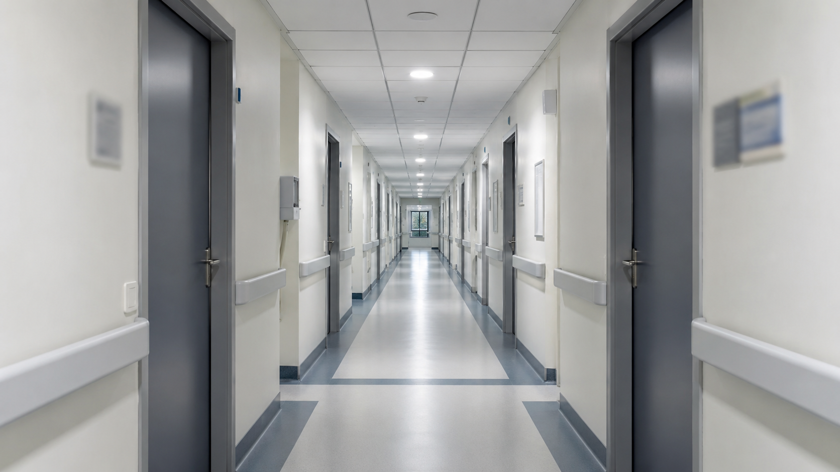 Long couloir vide d'un hopital public moderne, portes fermees, lumiere neutre