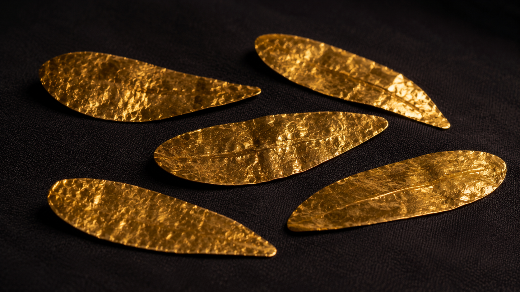 Fines feuilles d'or antiques en forme de langues, posées sur un tissu sombre