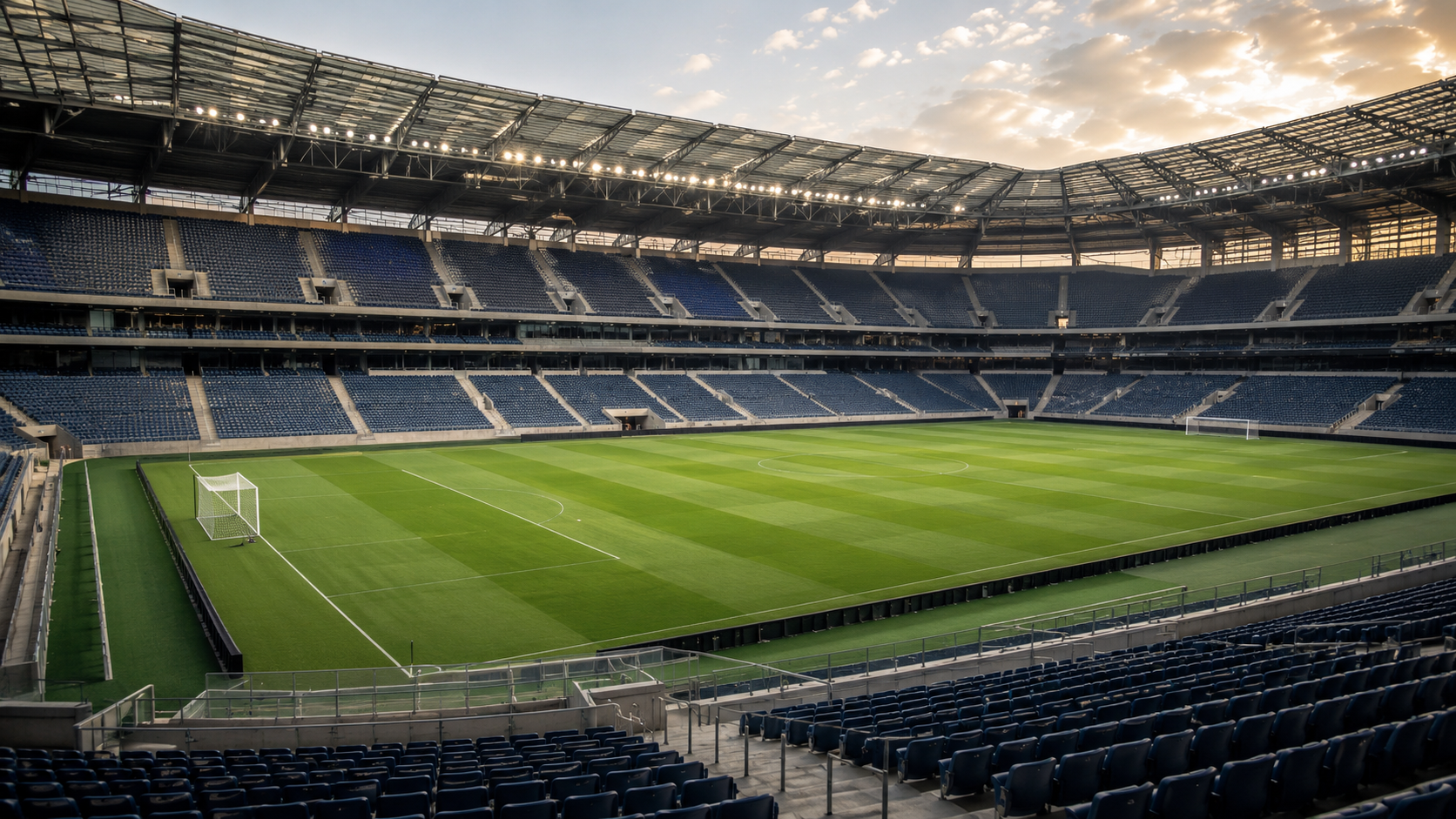 Pelouse verte d'un grand stade vue des tribunes en fin de journée, sans public