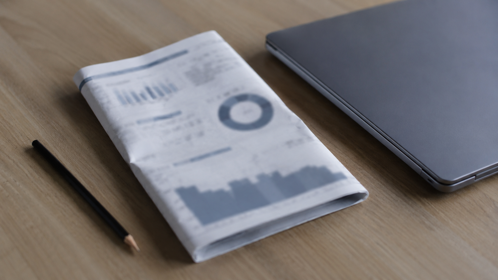 Un rapport statistique et un crayon posés sur un bureau, à côté d'un ordinateur fermé