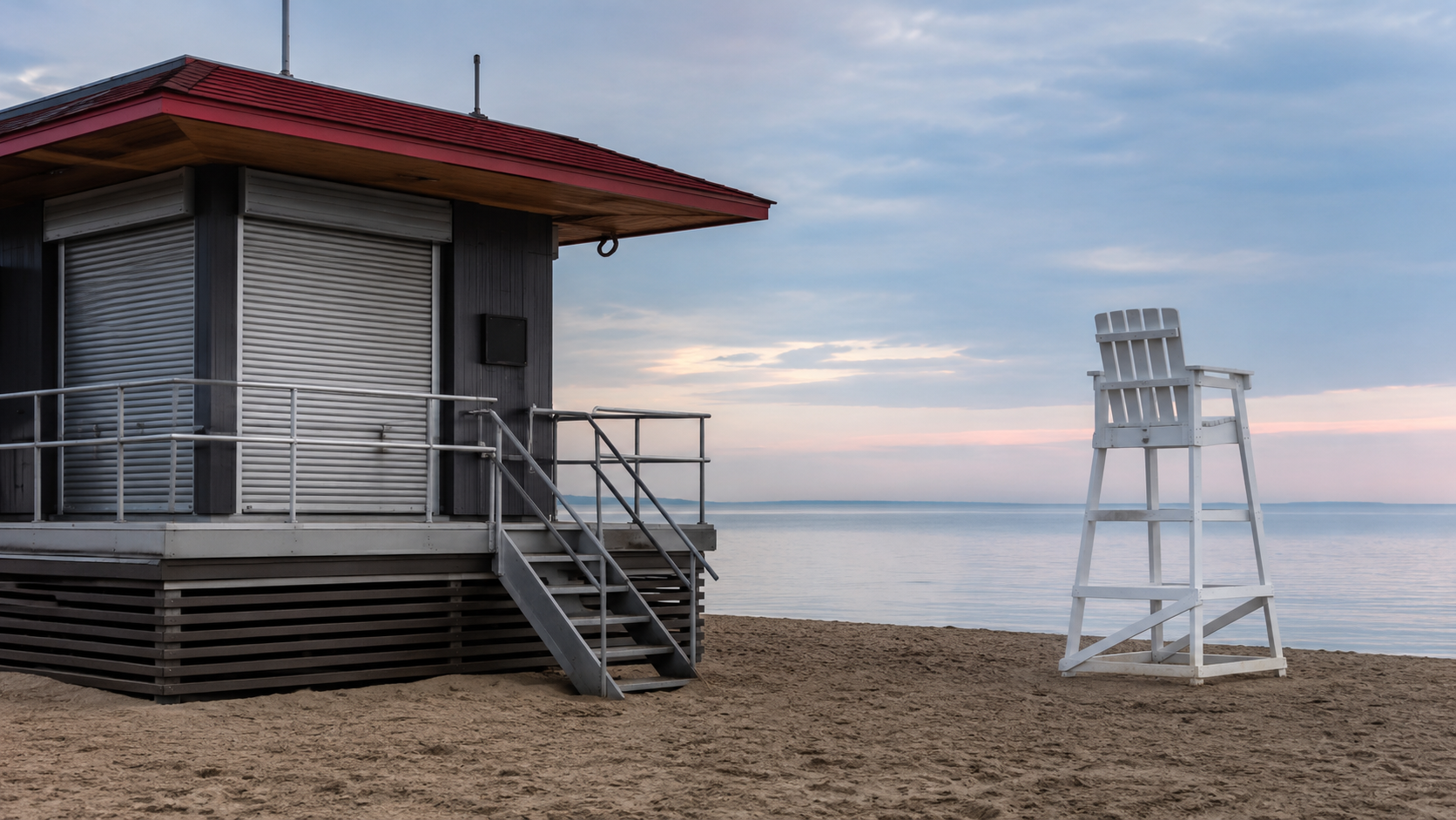 Un poste de secours de plage fermé, chaise d'observation vide, mer calme en fond