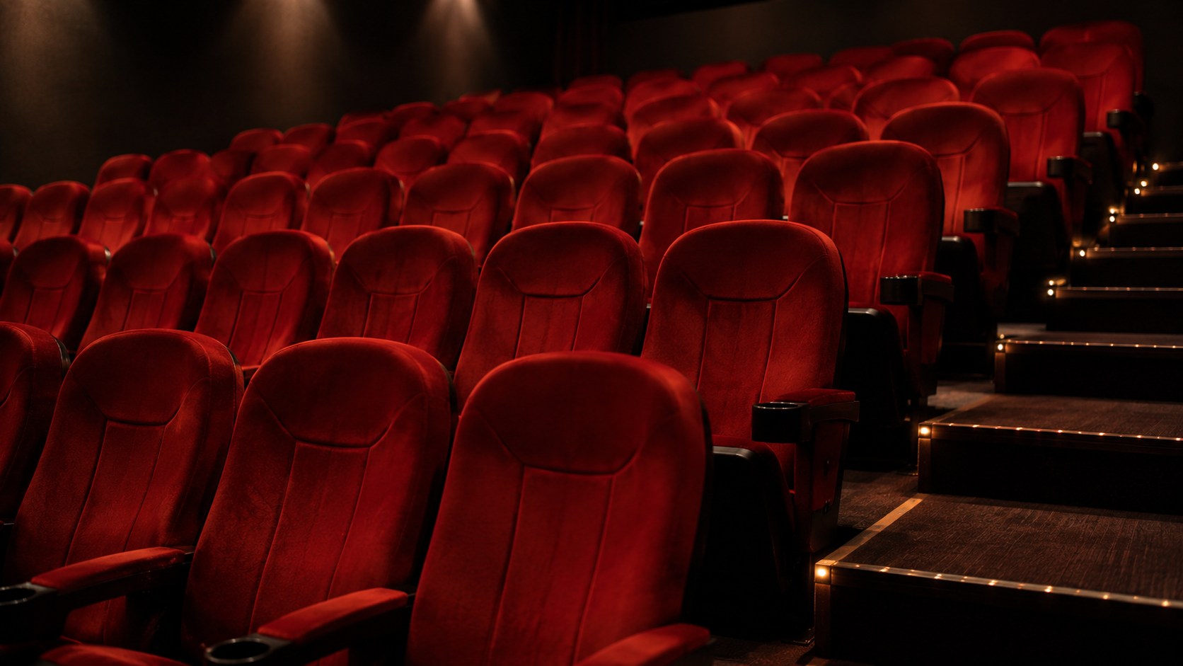 Rangées de sièges de cinéma vides dans une salle sombre
