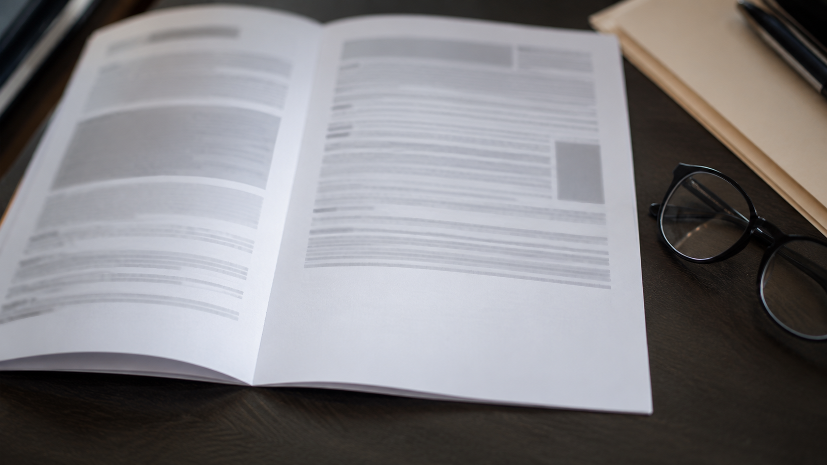 Un document imprimé ouvert sur un bureau, à côté de lunettes de lecture, avec une marge basse vide