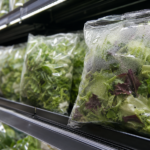 Linéaire réfrigéré de supermarché garni de sachets de salade sans étiquette lisible