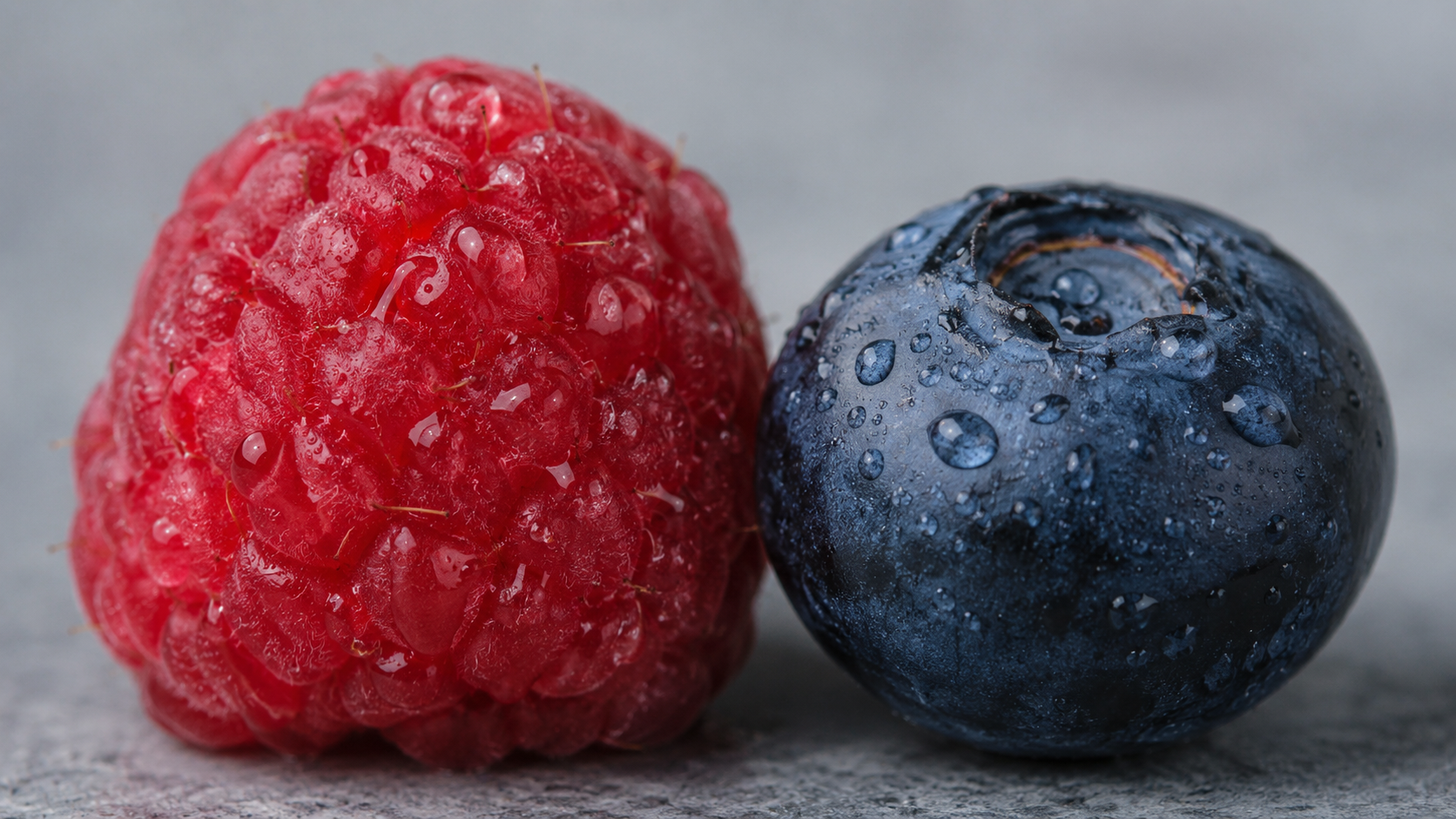 Gros plan d'une framboise et d'une myrtille mouillées côte à côte, creux contre peau lisse