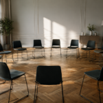 Salle de séminaire vide, chaises disposées en cercle sur un parquet, lumière du jour venant d'une grande fenêtre