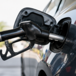 Pistolet de distribution posé dans la trappe à carburant ouverte d'une voiture, en gros plan