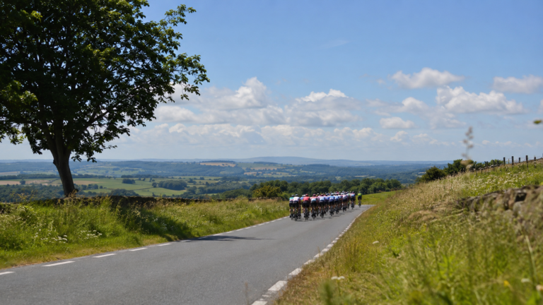 Peloton cycliste féminin vu de loin sur une route de campagne en été.