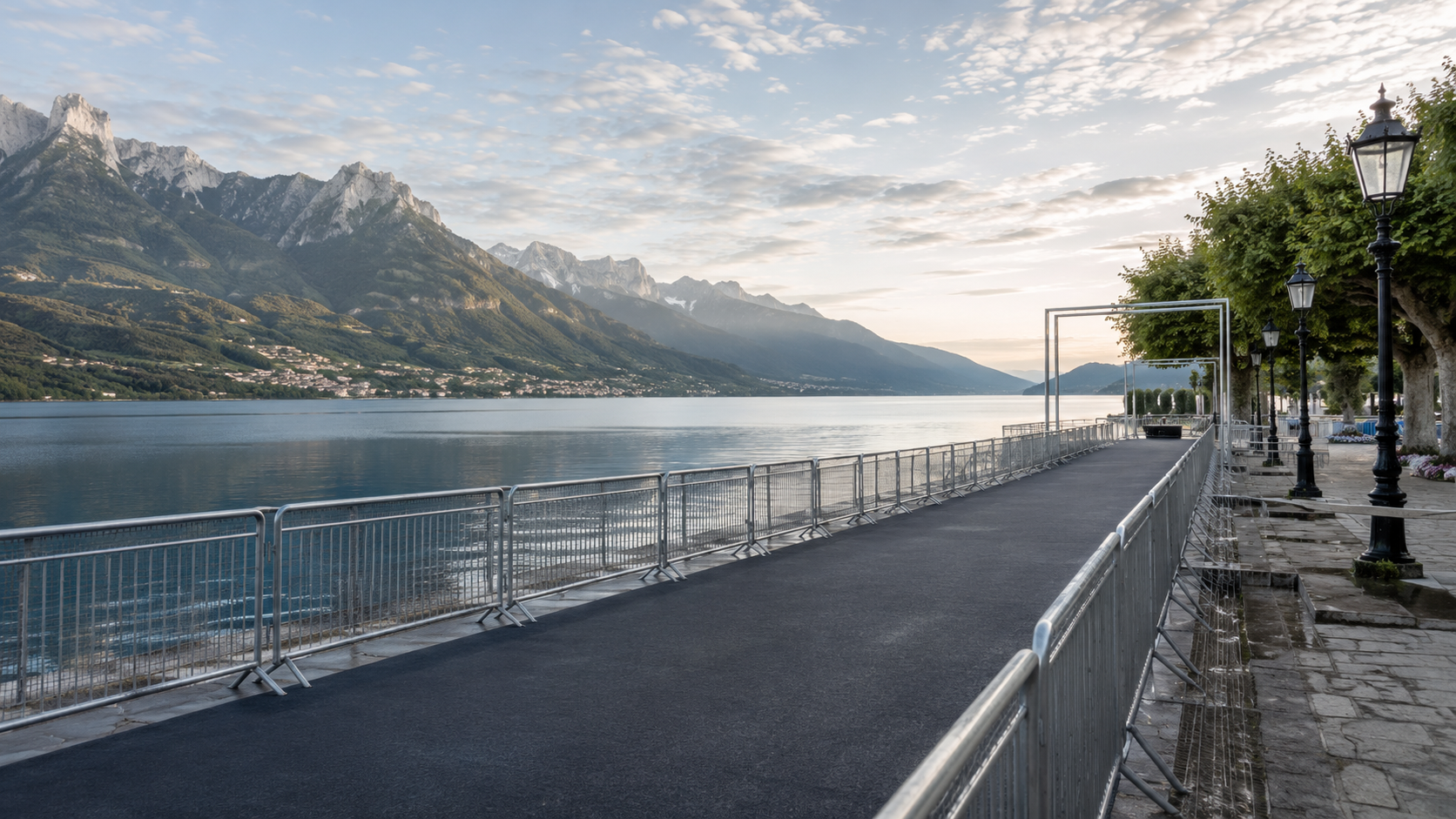 Zone de départ au bord d'un grand lac alpin au matin, barrières le long de l'eau et montagnes au loin