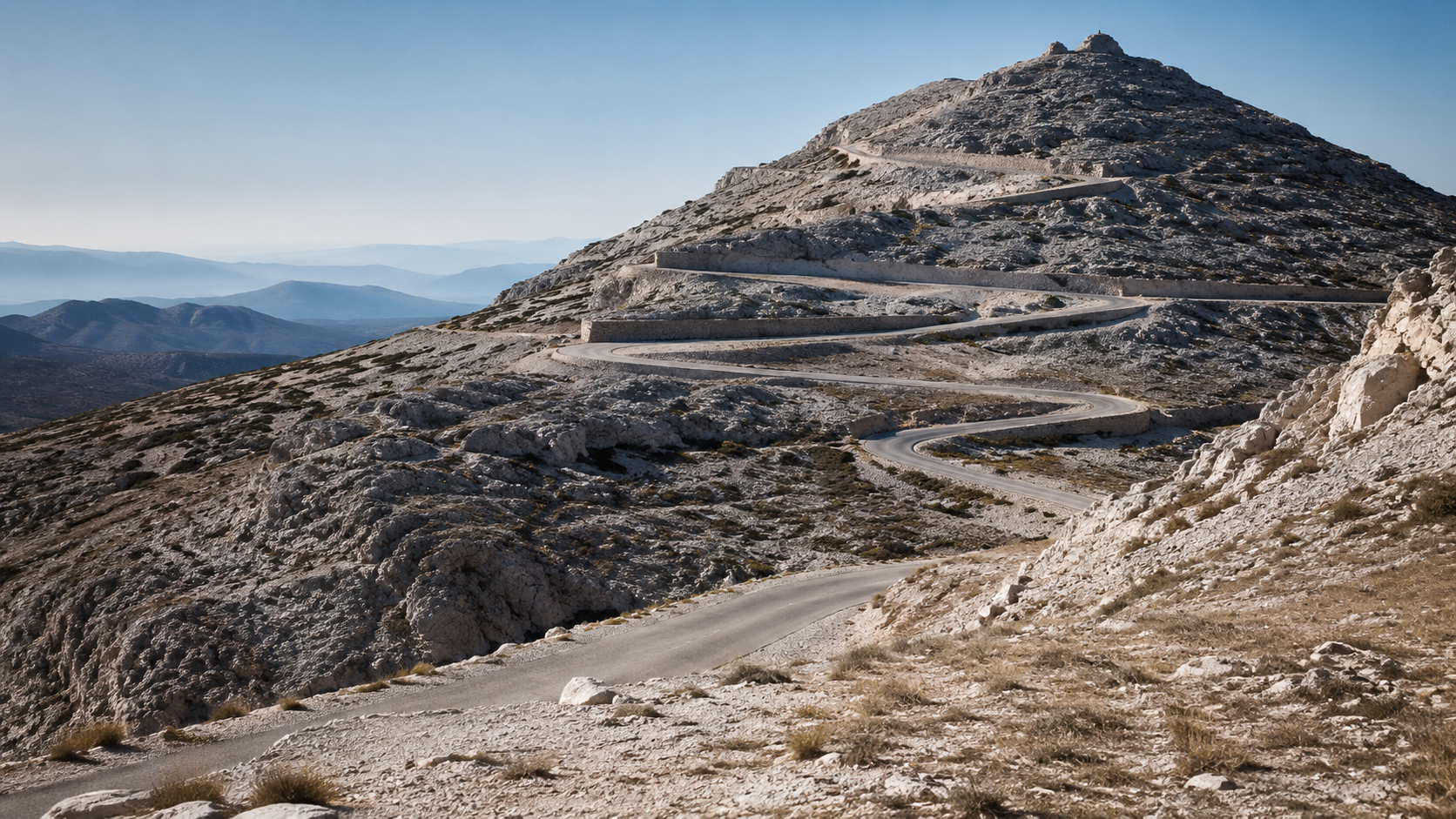 Route sommitale de calcaire blanc d'une montagne provençale serpentant vers un pic rocheux sous une lumière dure