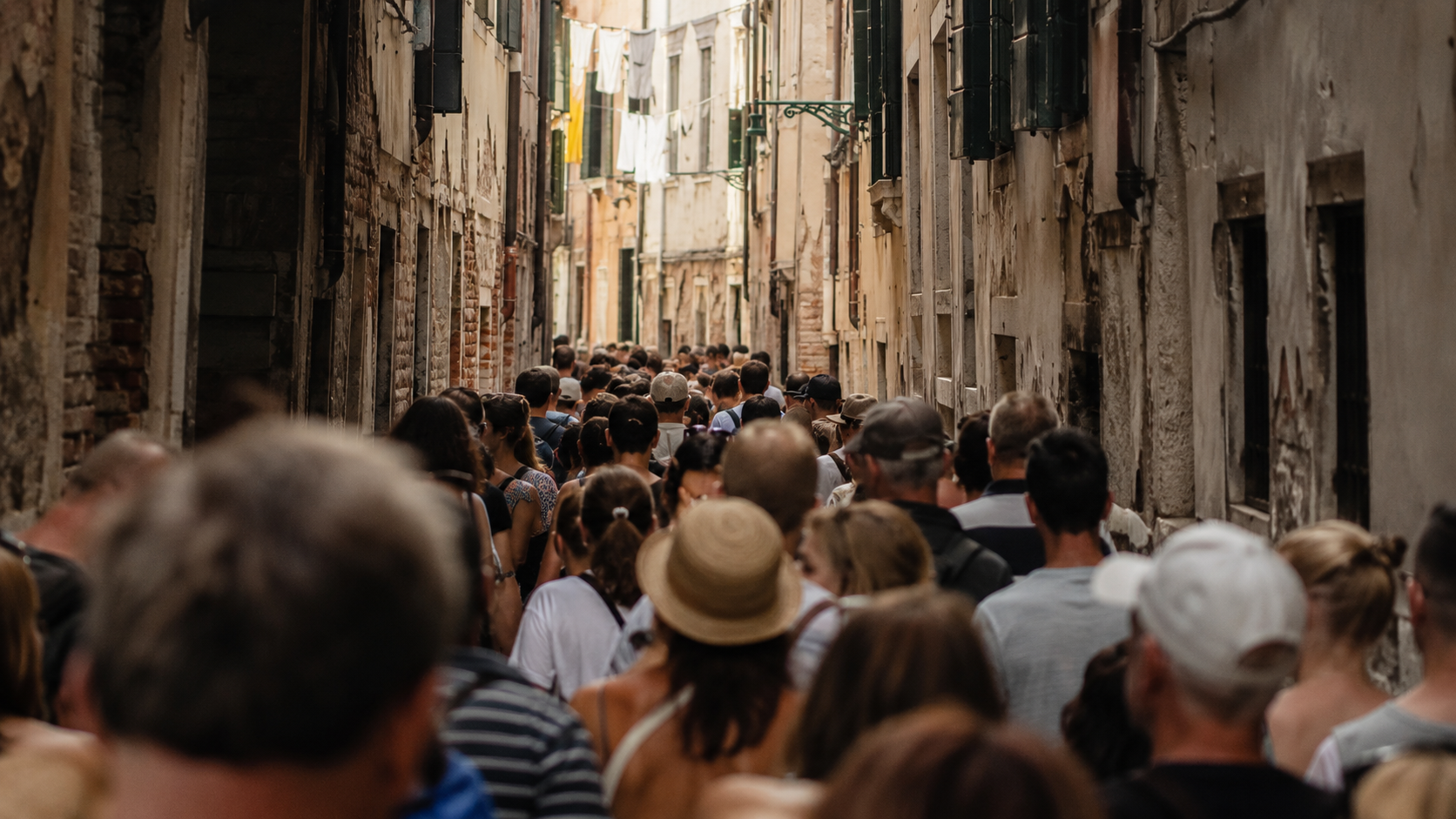 Ruelle venitienne etroite saturee d'une foule anonyme de touristes, fils a linge et volets au-dessus