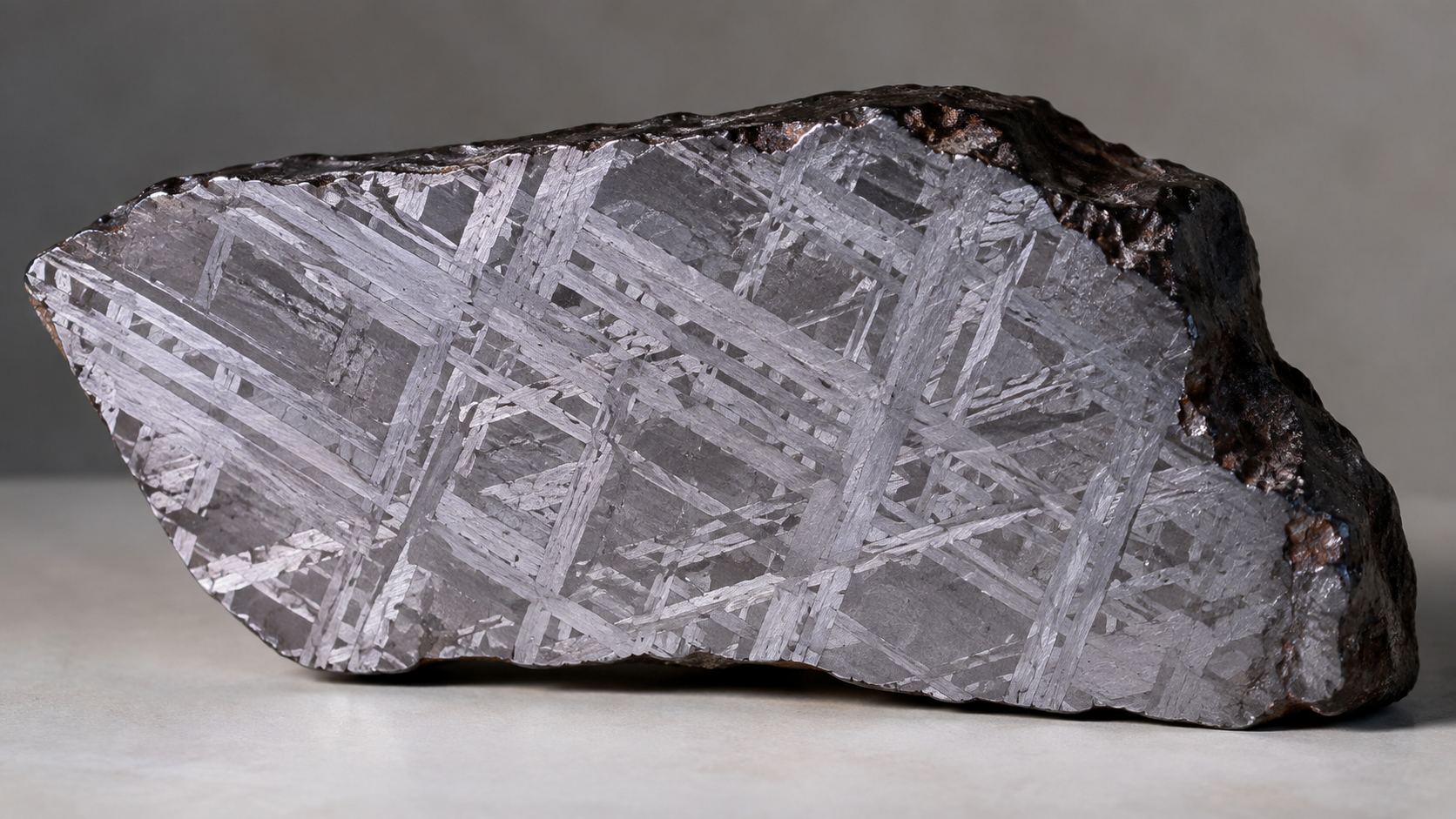 Tranche polie de météorite de fer où apparaît un réseau de bandes métalliques entrecroisées.