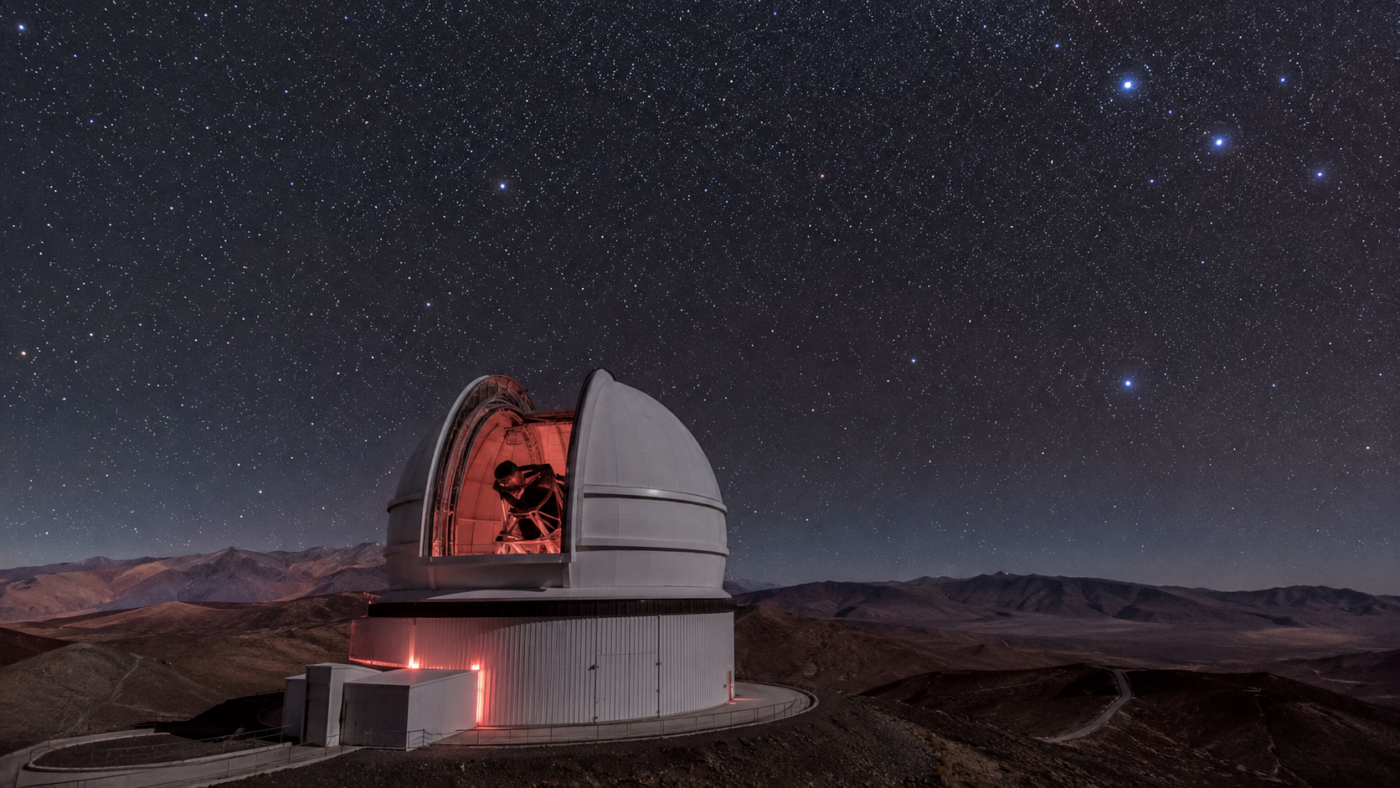 Coupole de télescope ouverte la nuit sous un ciel dense d'étoiles, sur une crête désertique d'altitude