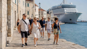 Paquebot de croisière blanc amarré à un terminal portuaire méditerranéen en fin de journée, passerelle déployée vers le quai.