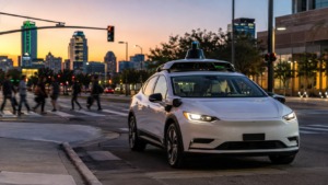 Voiture électrique blanche équipée de capteurs sur le toit, arrêtée à un carrefour urbain au crépuscule, siège conducteur vide, passants flous en arrière-plan.
