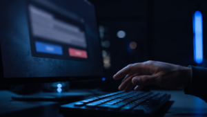 Main d'une personne au-dessus d'un clavier, devant un écran de terminal affichant une demande d'autorisation à deux boutons, dans une pièce sombre.