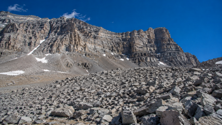 Champ de blocs rocheux gris et anguleux s’étalant au pied d’une paroi raide de haute montagne dans l’Ouest américain, ciel bleu profond