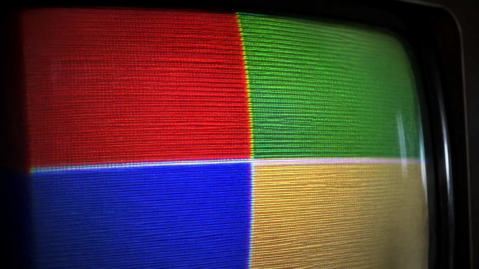 Macro d’un écran cathodique montrant de gros blocs de pixels abstraits en quatre couleurs plates, avec lignes de balayage