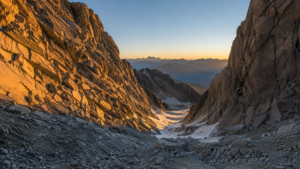 Couloir rocheux du massif du Mont-Blanc au lever du jour, parois de granit sèches striées de traces d’éboulement, neige résiduelle en fond de couloir.