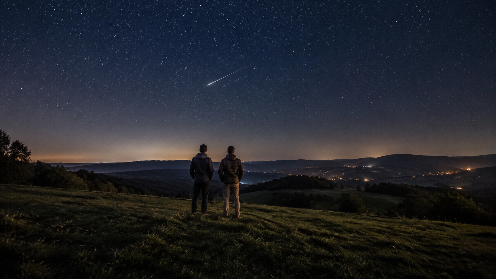 Un coteau rural sous un ciel étoilé, une traînée de météore et deux silhouettes debout qui regardent vers le haut.