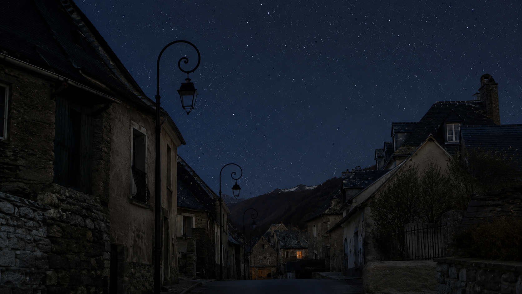 Une rue de village aux lampadaires éteints la nuit, étoiles visibles au-dessus des toits.