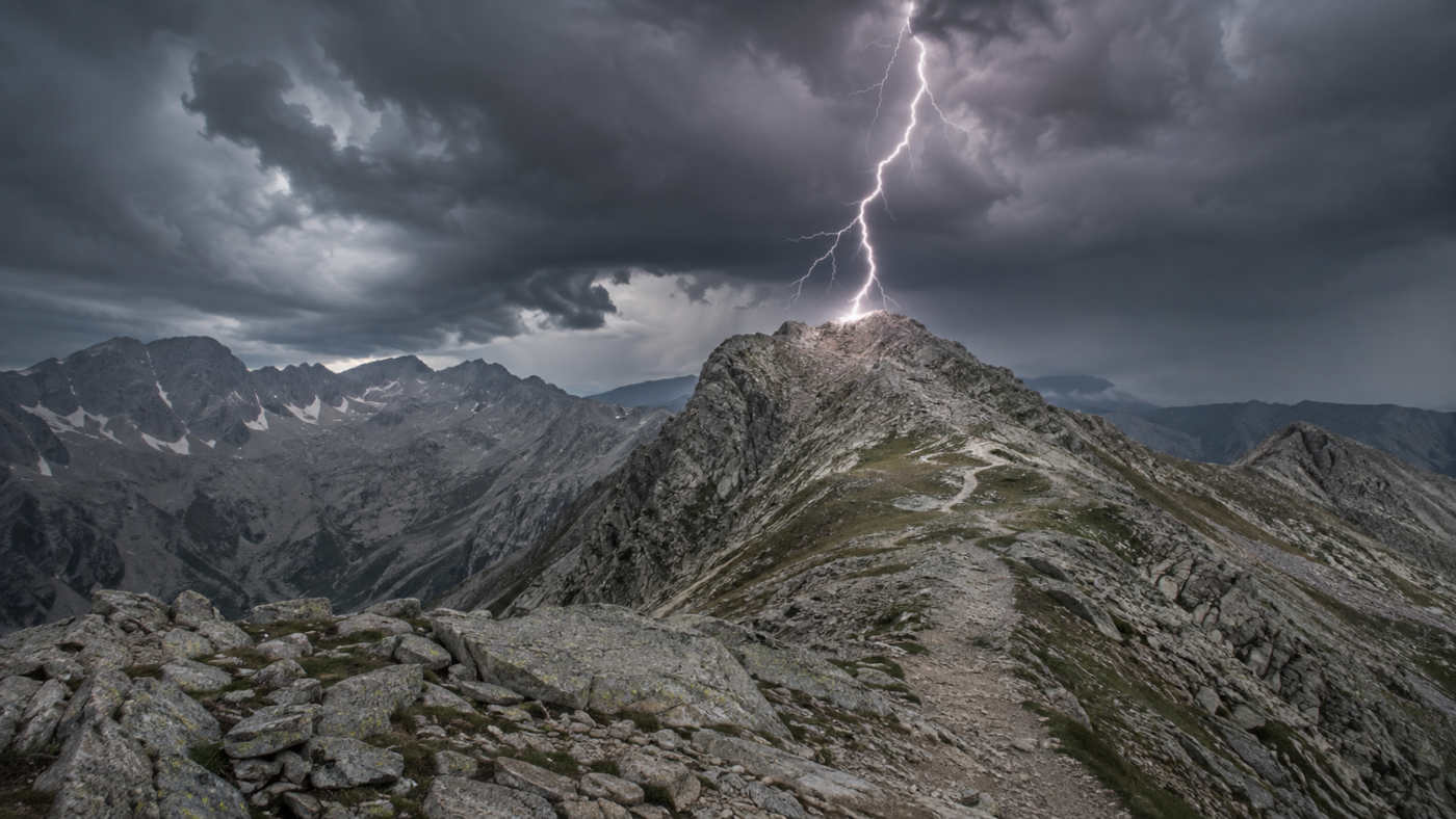 Orage violent au-dessus d'une crête granitique des Pyrénées vers 2 700 mètres, un éclair frappant une arête rocheuse dénudée au-dessus d'un sentier de randonnée.