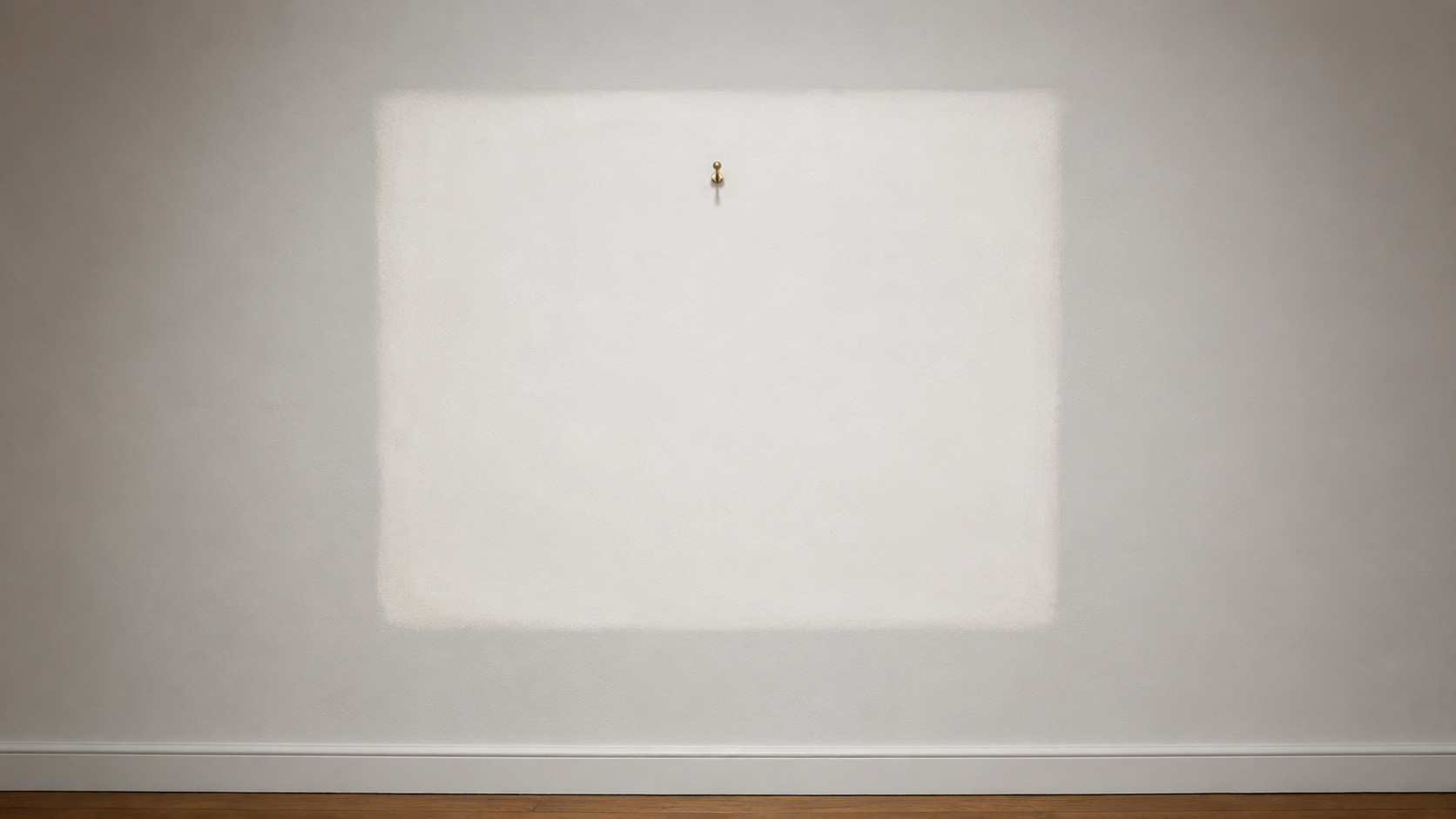 Mur blanc de galerie où se devine le rectangle plus clair laissé par un cadre décroché, avec un crochet vide au-dessus