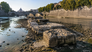 Blocs de pierre antiques usés émergeant d’un fleuve très bas, entre deux quais de pierre en ville.