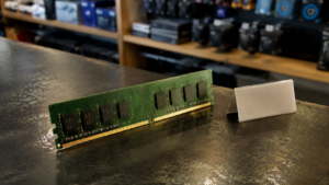 Barrette de mémoire vive posée sur un comptoir de magasin à côté d'une étiquette de prix retournée, sans marque ni texte lisible
