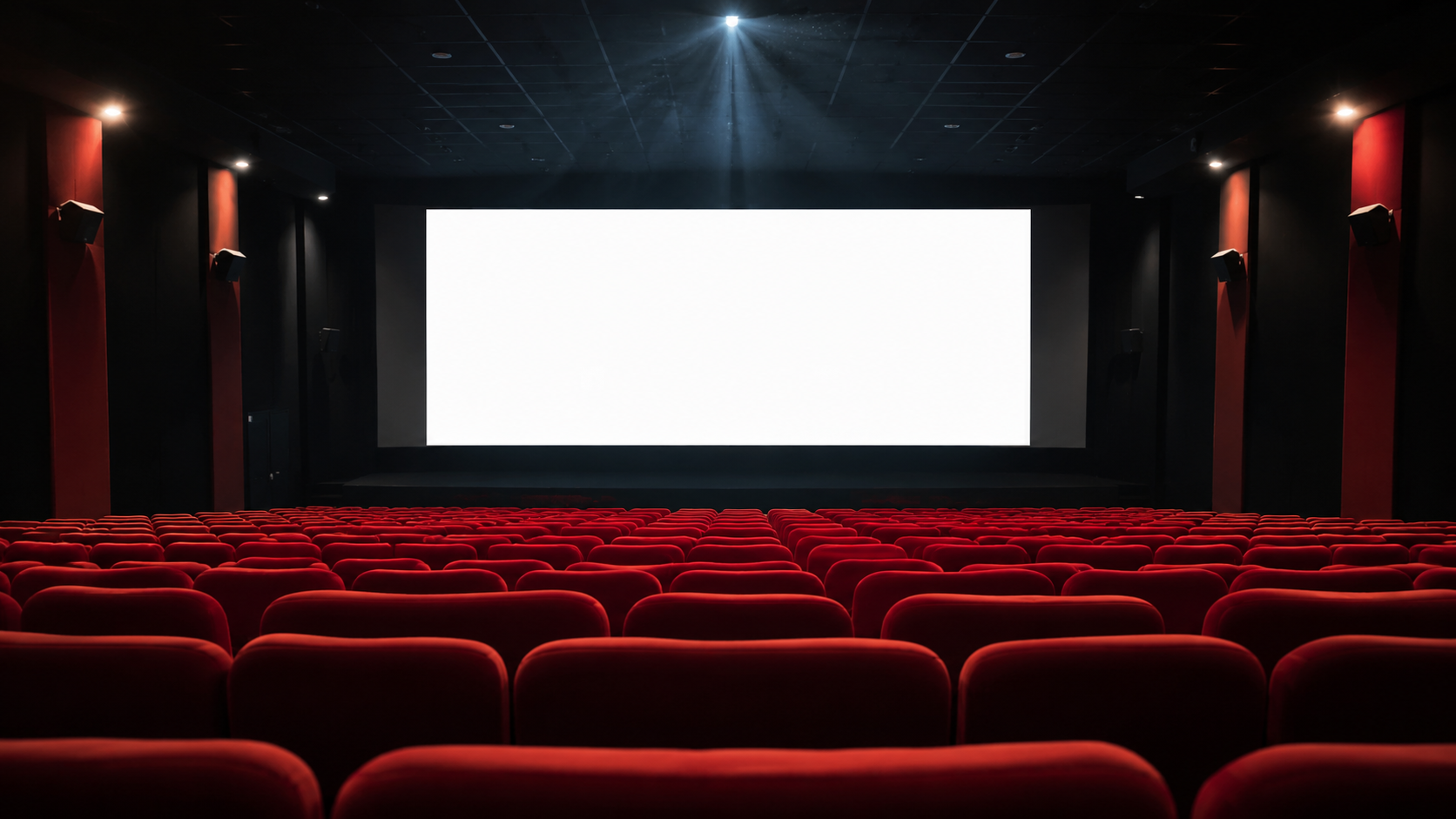 Salle de cinéma vide vue du fond : rangées de fauteuils rouges et faisceau du projecteur traversant l'obscurité vers un écran blanc.