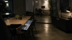 Main tenant un téléphone à l'écran flou dans un intérieur de bureau sombre