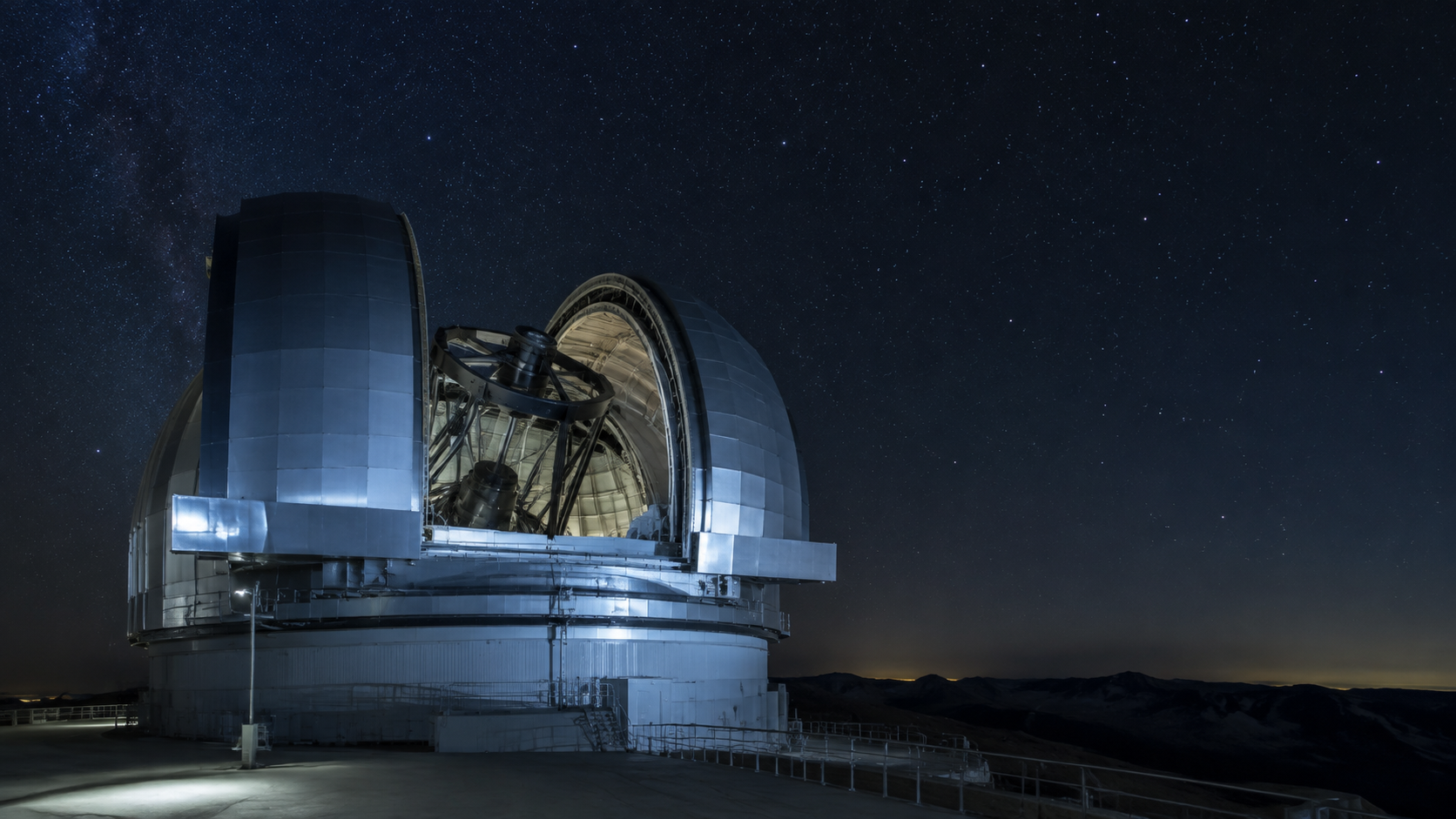 La coupole ouverte d'un grand télescope au sol, tournée vers un ciel étoilé, sans personne visible.