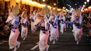 Des danseurs en yukata et chapeau de paille amigasa défilent la nuit entre deux haies de spectateurs, sous des lanternes de papier.