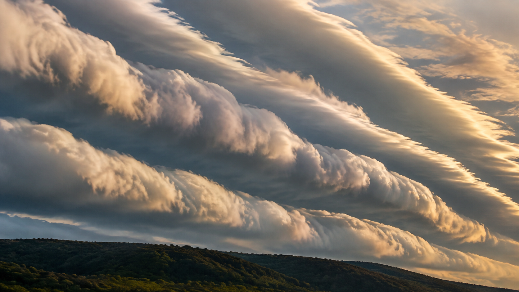 Rangée de nuages enroulés en vagues déferlantes alignées dans un ciel de fin de journée, au-dessus d'une crête boisée.