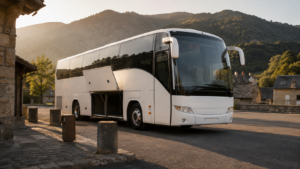 Un autocar blanc stationné sur une petite gare routière de village de montagne, soute ouverte, dans la lumière dorée de fin d'après-midi, sans personne aux alentours.